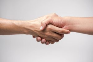 Two hands shaking against white background