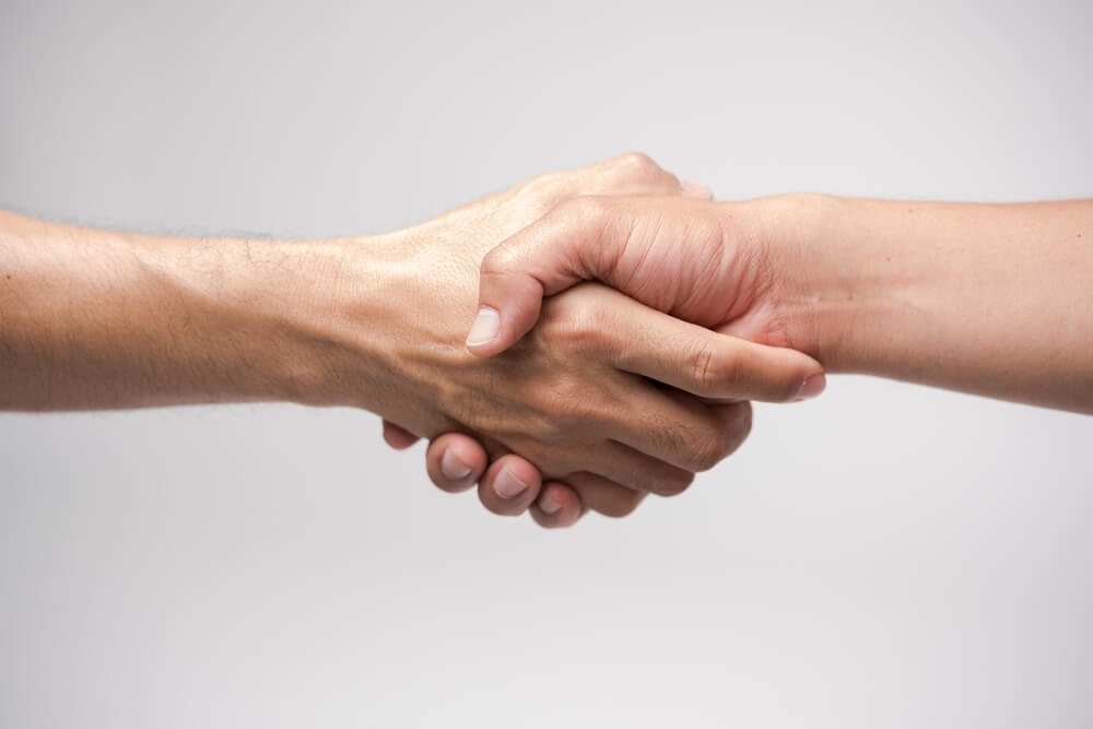 Two hands shaking against white background