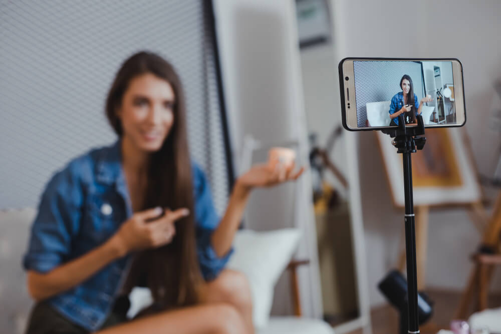 Smiling influencer filming herself on smartphone holding product