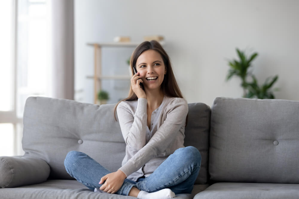 women sitting on the sofa and talking in the phone 