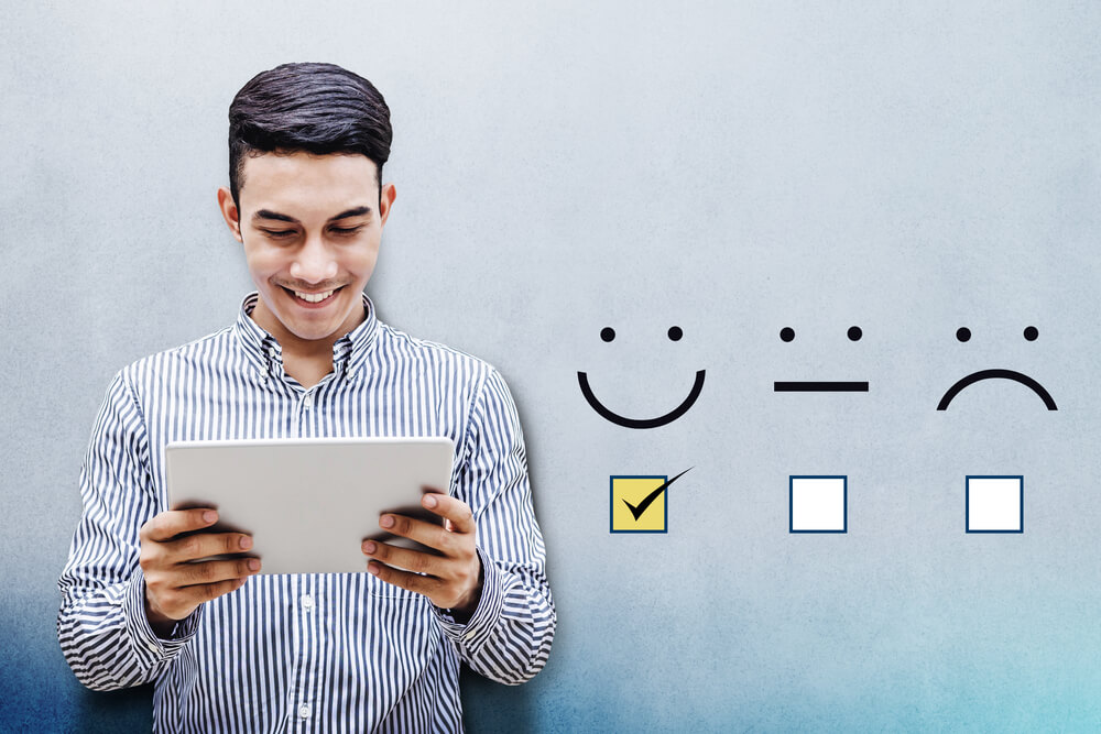 Man holding digital tablet with a checked box on excellent smiley 

