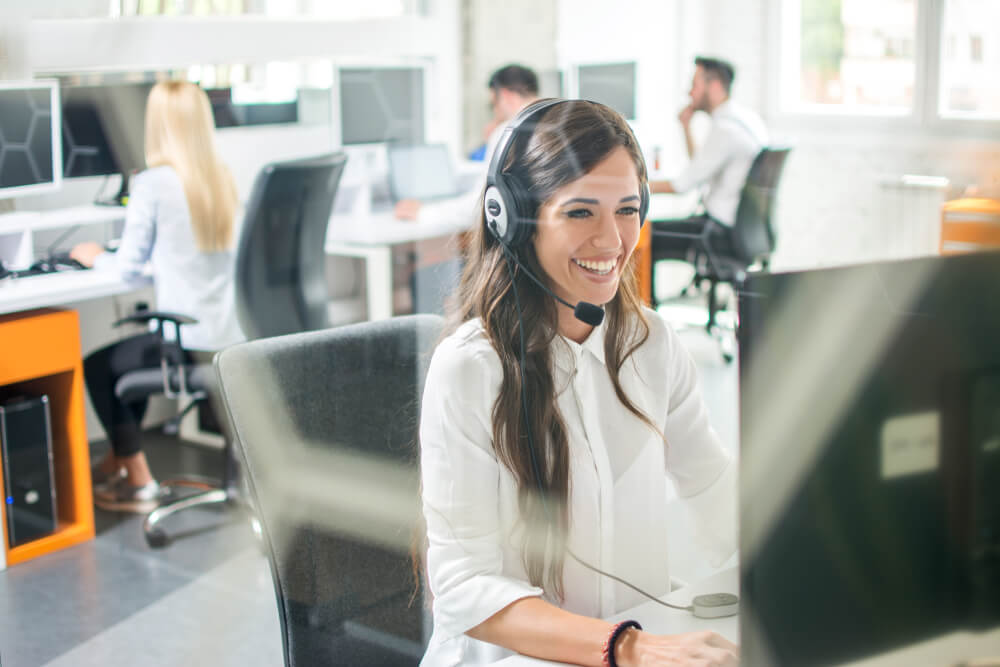 smiling women wearing headset and using computer 