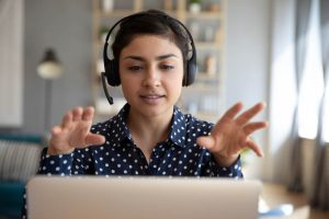 Female receptionist with headset in front of laptop speaking to customer