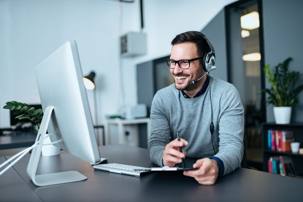 man smiling and watching his computer screen