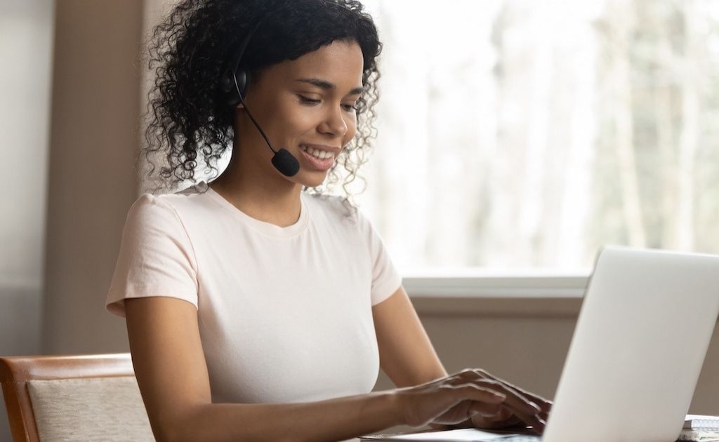 Woman working at a telephone answering service, using a headset to answer calls.