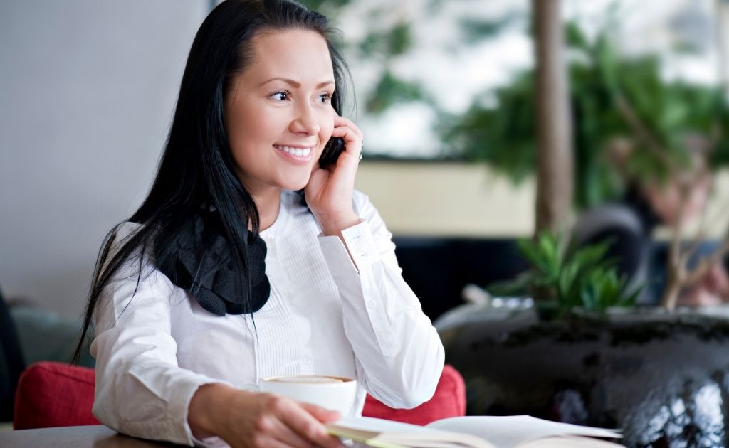 Smiling woman on the telephone, dealing with an angry caller.