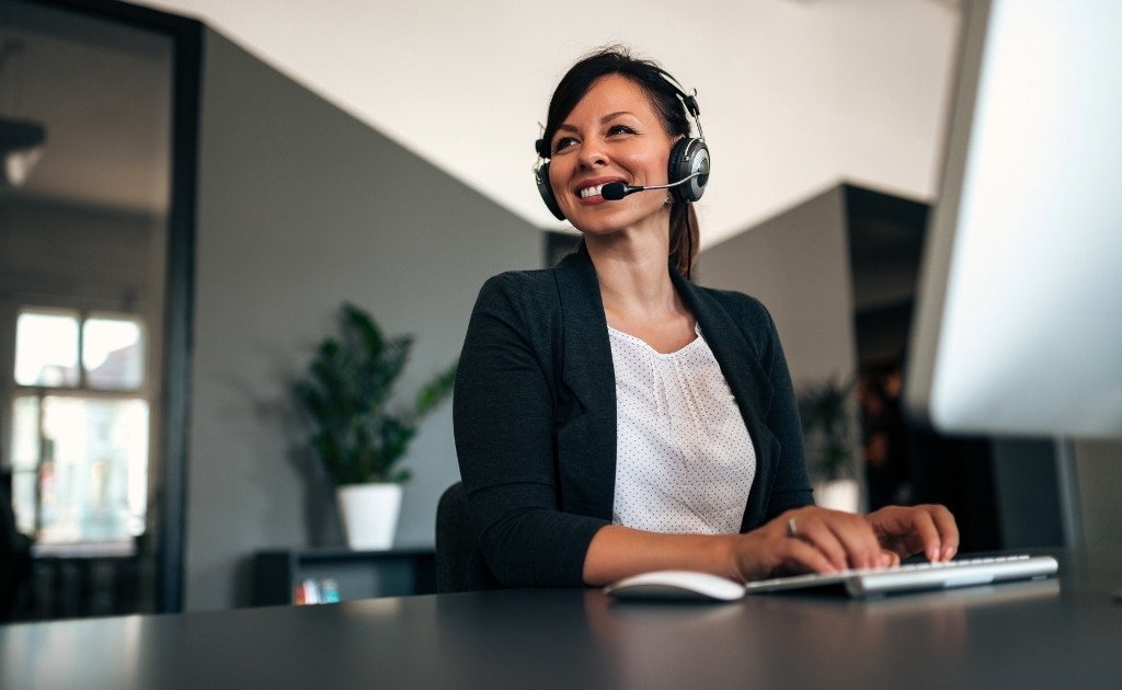 Smiling Woman working in an office environment, taking calls for her call handling service job. 