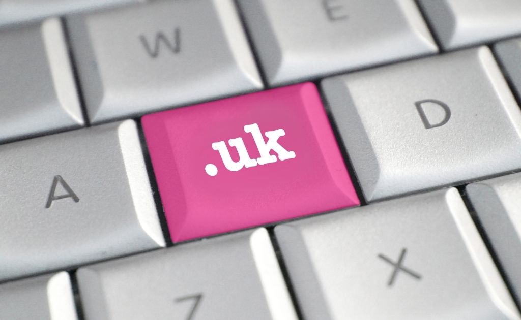 White computer keyboard, featuring a pink button with .uk on it. Having a UK based website helps to create a business presence.