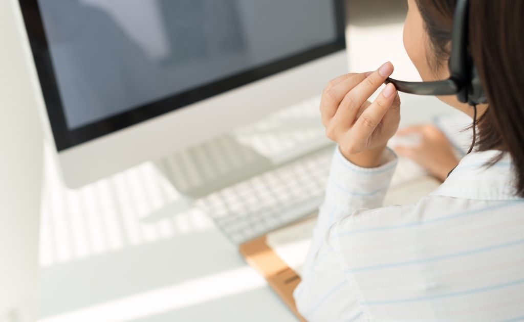 Woman sitting in front of a computer screen, answering a calls as virtual assistants.