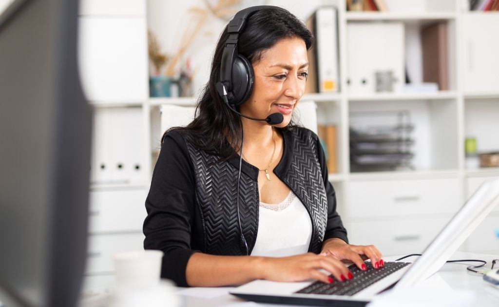 Smiling female receptionist using call forwarding technologhy to patch caller through to a salesperson