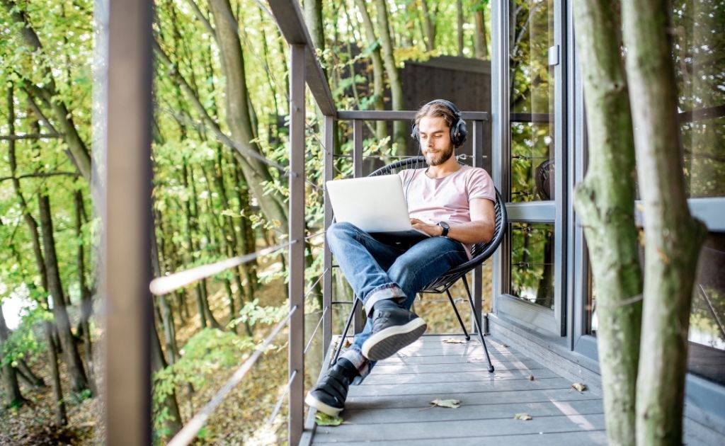 Man with headphones and a laptop, engaging in remote work while sitting outside.