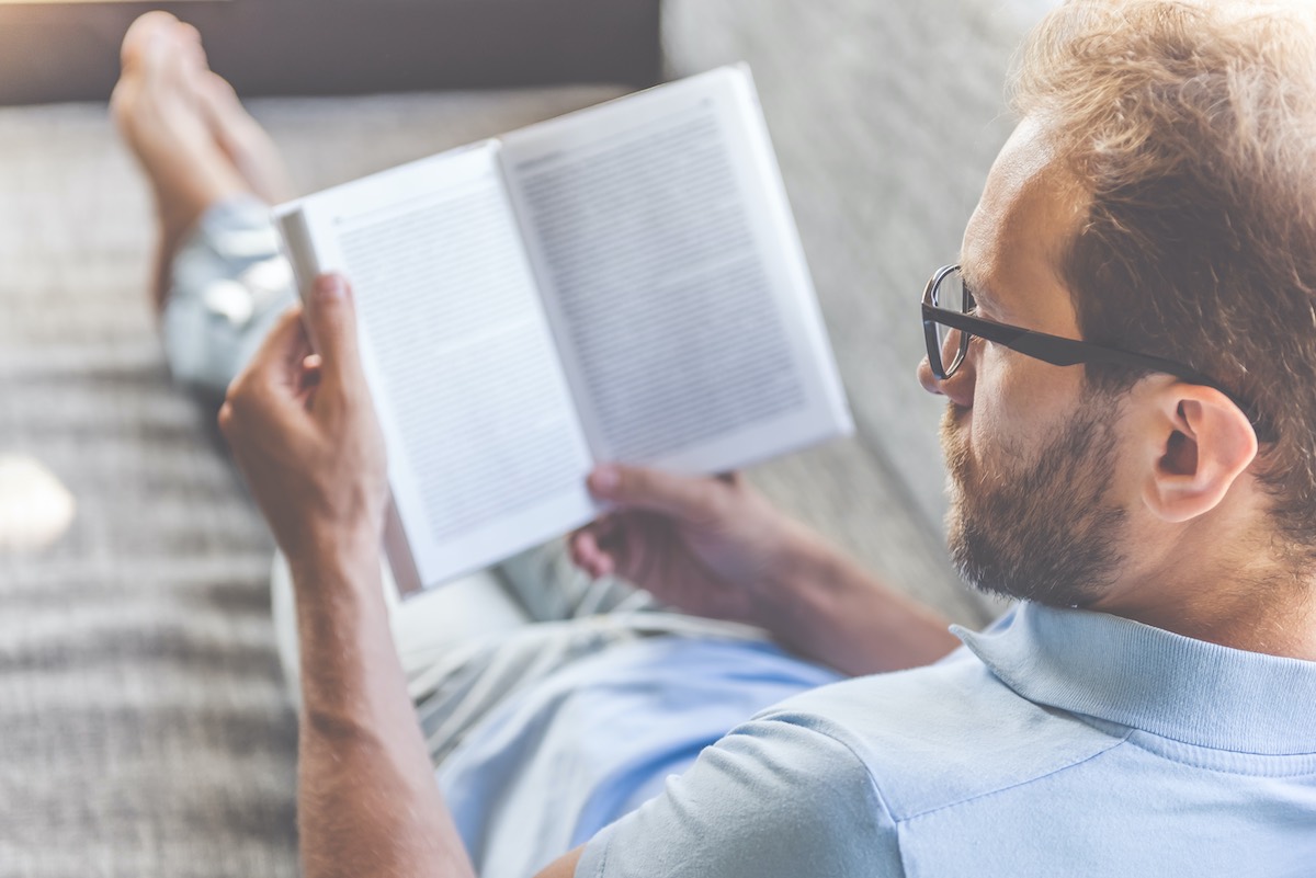 Man sat on sofa reading book as part of learning time