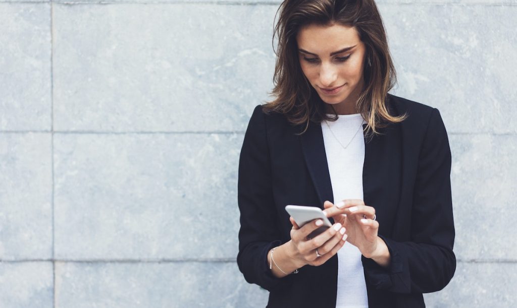 Woman smiling looking at smartphone for learning time