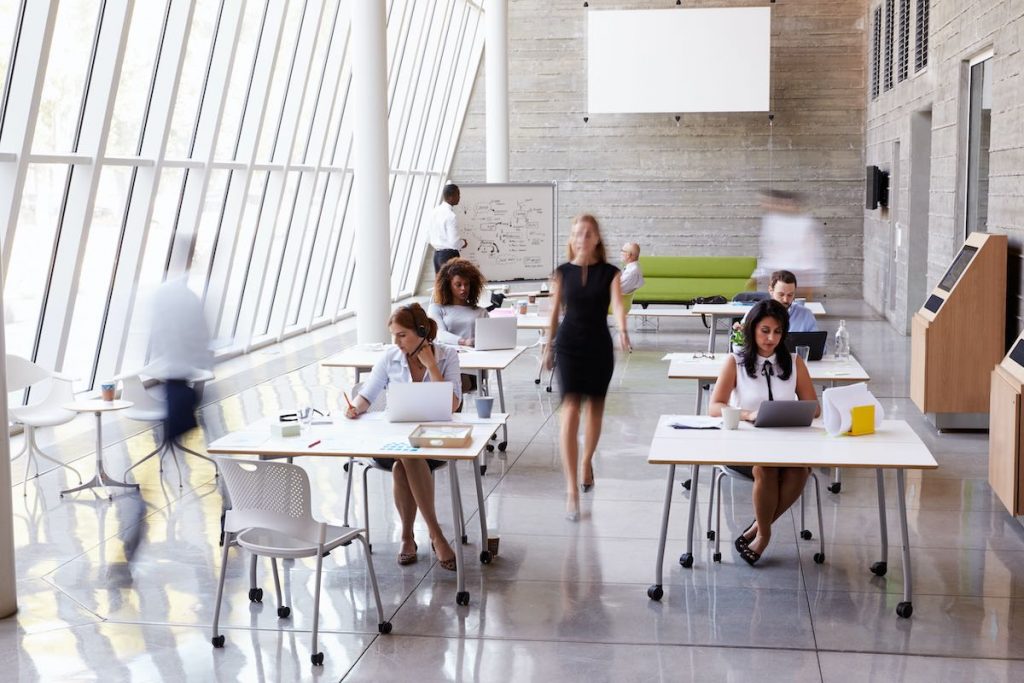 Overhead View Of Businesspeople on hybrid work pattern Working At Desks In Office