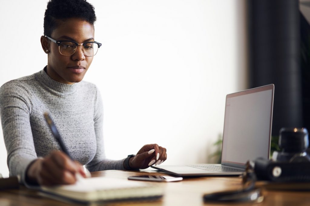 Female professional making notes on marketing campaign at laptop