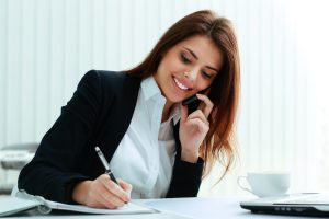 Smiling receptionist taking call using time-based 24/7 live answering service