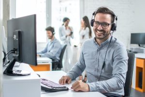 Happy male receptionist on headset answering calls for call centre service