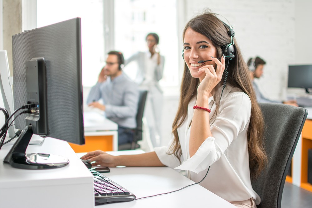 Smiling agent with headset answering calls for telephone answering service