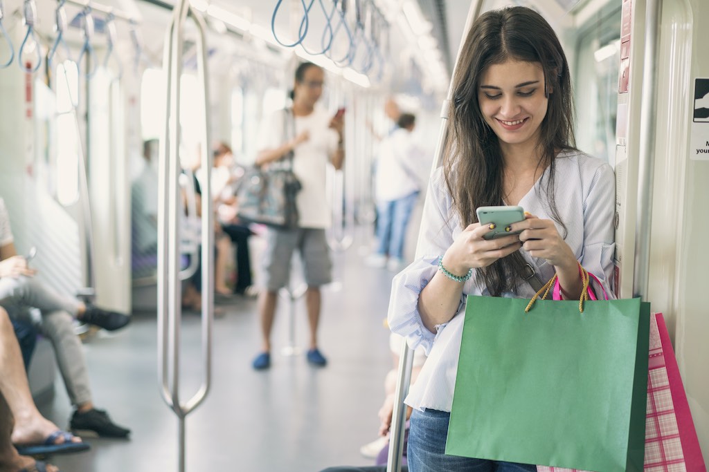 Smiling woman on public transport engaging in customer interaction on smartphone