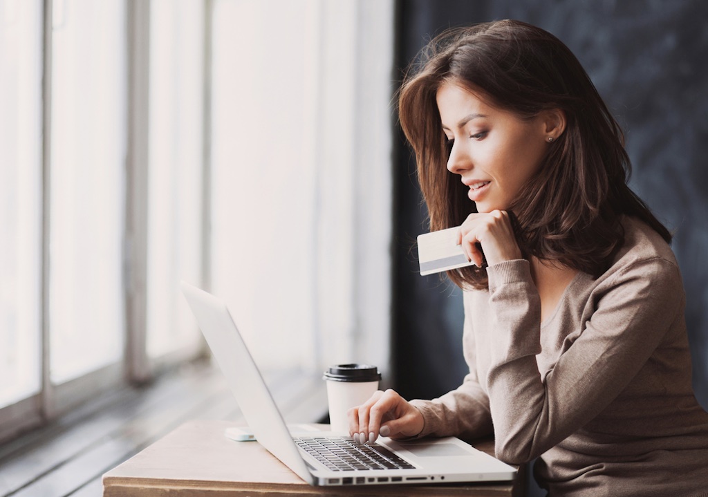 Young woman holding credit card and using laptop computer. Businesswoman working at home. Online shopping, e-commerce, internet banking, spending money, working from home concept