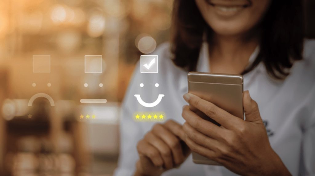 Woman selecting happy emoji icon on smartphone representing customer satisfaction