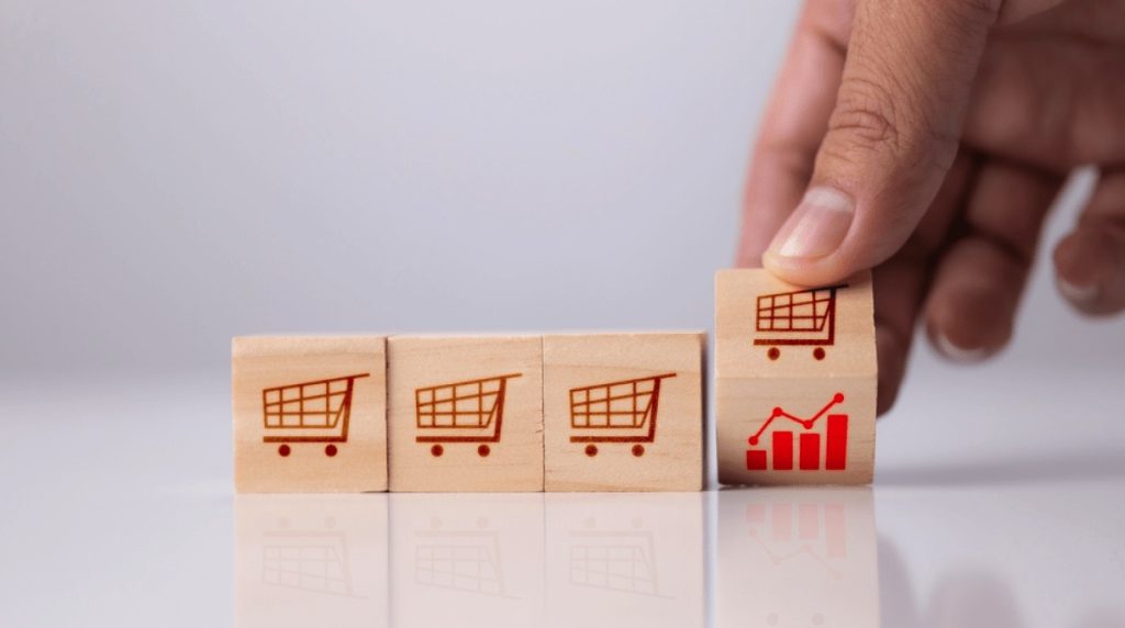 Four wooden blocks with shopping carts and final block showing graph to represent customer lifetime value increasing