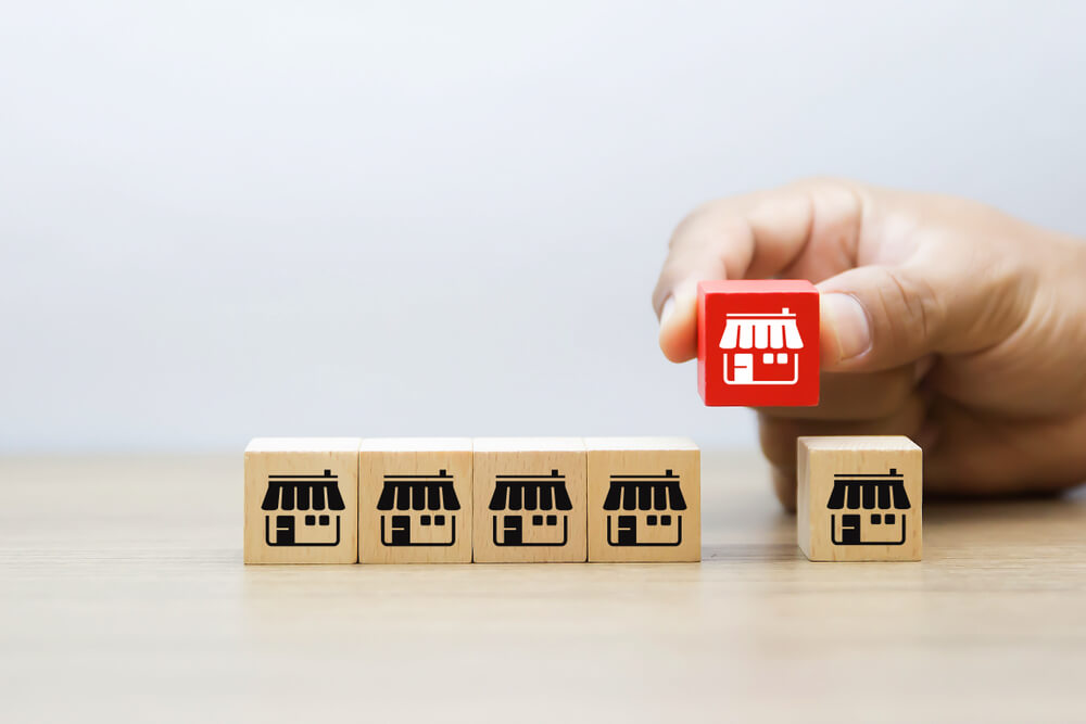 Hand holding a red block with a shop icon