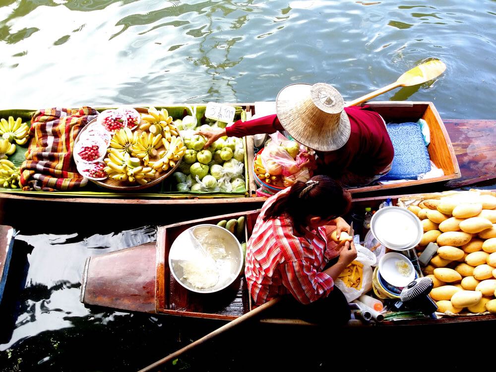 Aerial shot of a person selling produce on a boat in a river market in Thailand