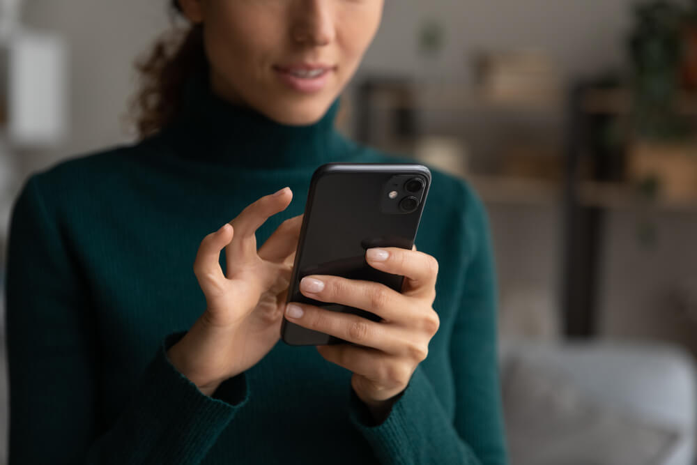 Woman in green jumper typing on smartphone