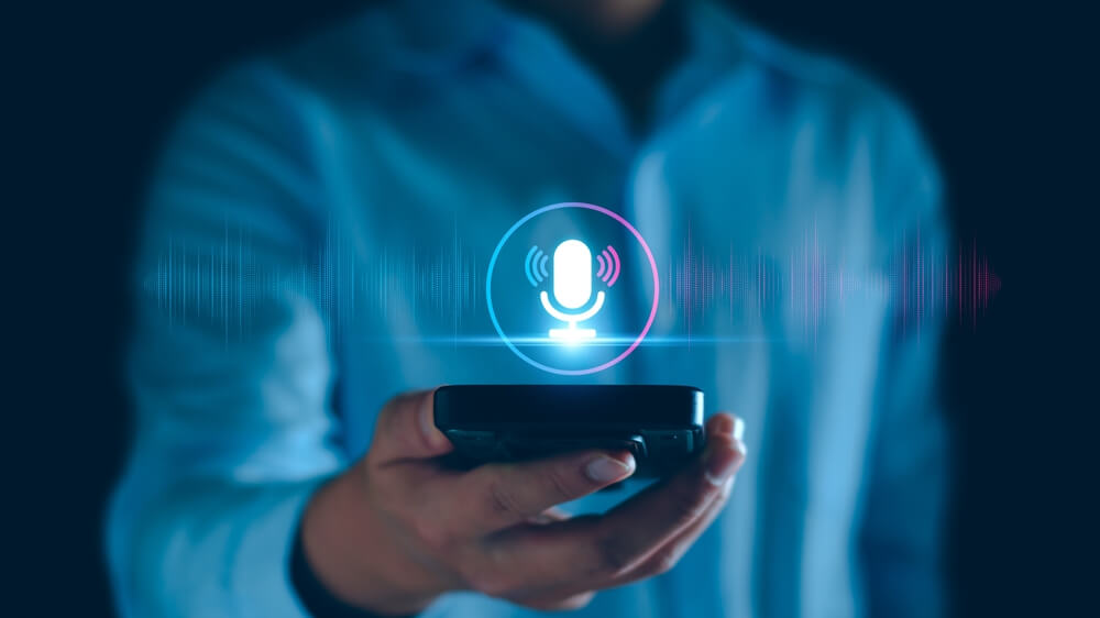 Man holding phone with microphone icon showing voice search