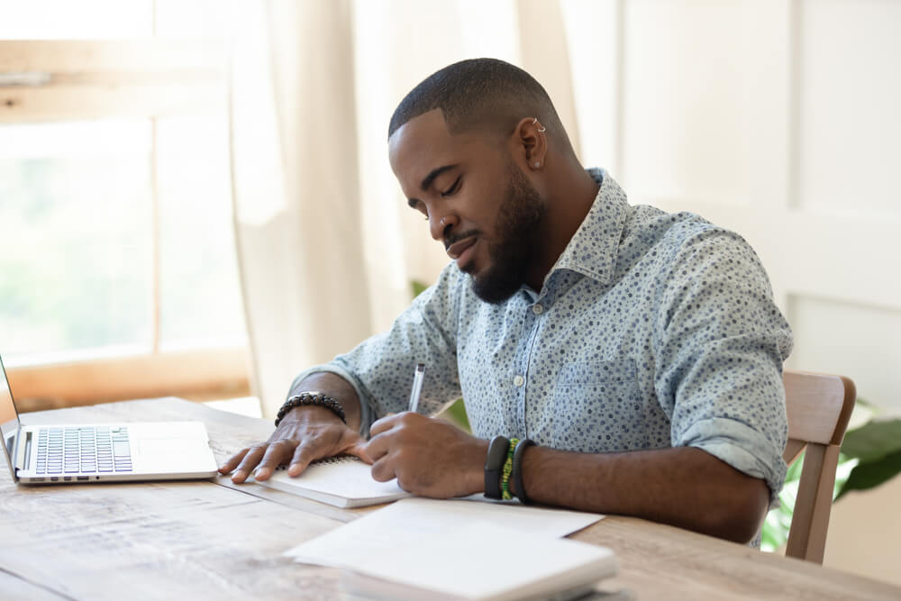 Man making notes in notepad at desk
