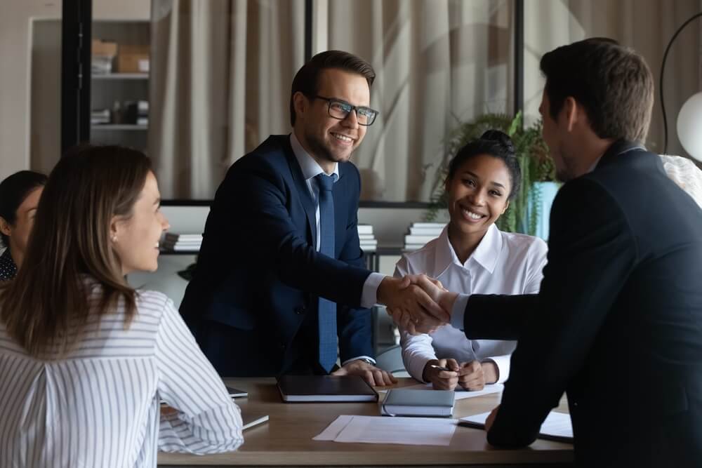 New employee shaking hands with business owner in office meeting room
