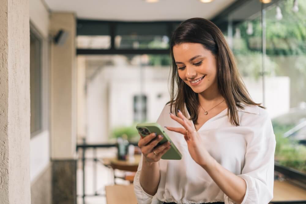 Smiling woman looking at smartphone in home setting

