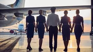 pilot and airhostess walking on runway where 2 planes are parked.