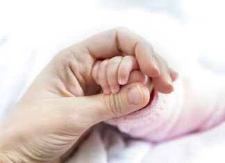 feb mothers hand holding newborn babys hand medium e