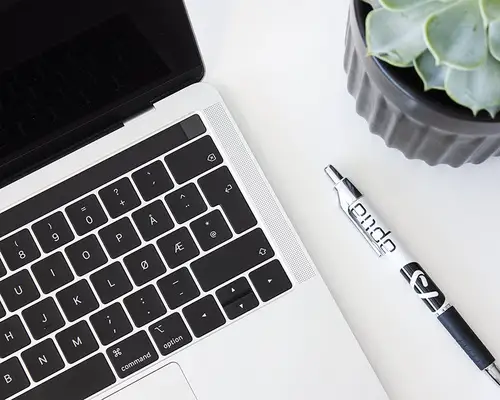 Et bilde av en hvit pult med en plante, en laptop og en penn med Aplia-logoen.