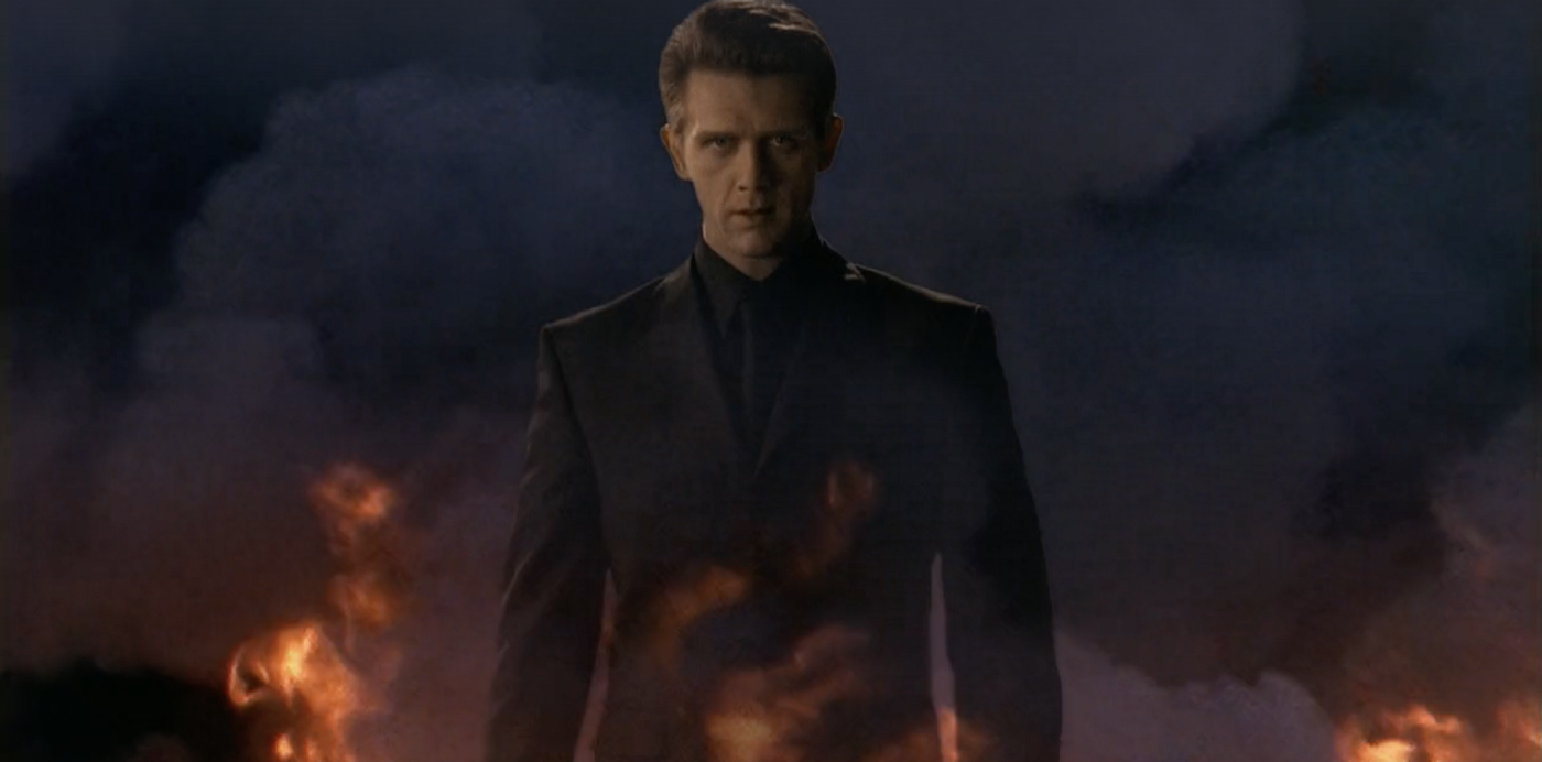 Nicolae looking particularly devilish and walking away from a fire at night.