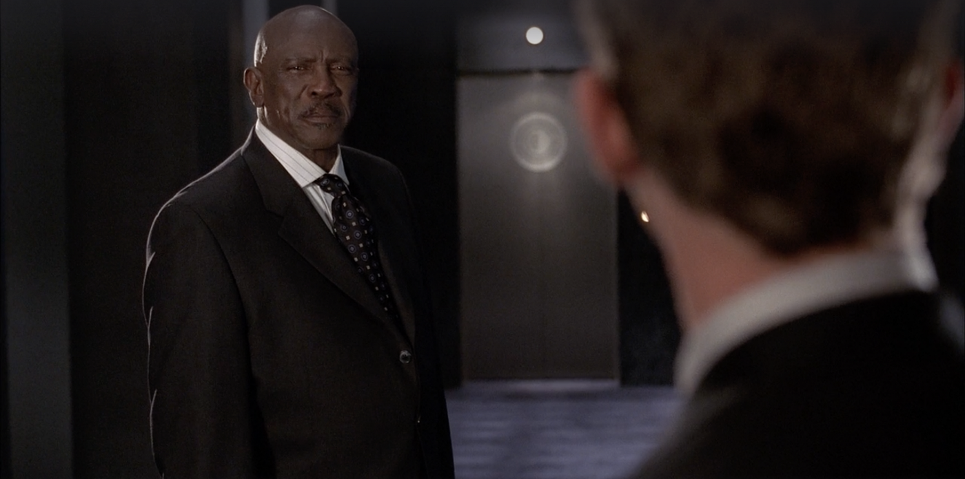 Lou Gossett Jr., who plays President Fitzhugh, looking serious. He is wearing a dark suit and has a moustache and a shaved head.