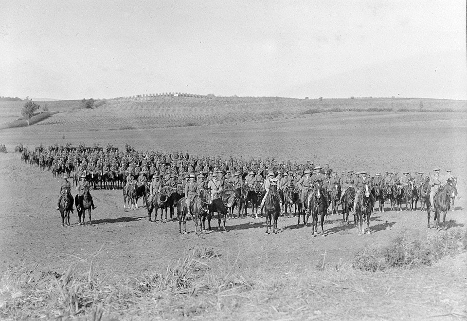 A column of men in uniform on horseback on a plain.