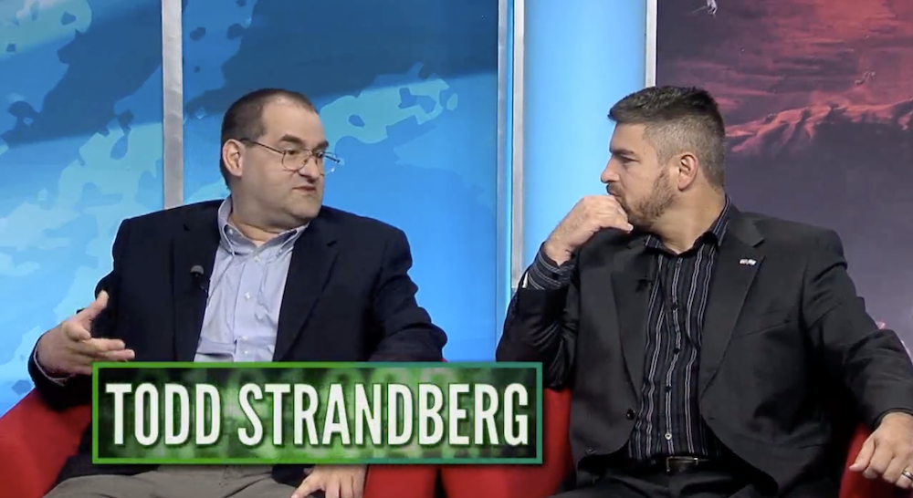 Todd Strandberg being interviewed by another dude with a gigantic green box with Strandberg's name in white text, which is very Sesame Street, superimposed below him.