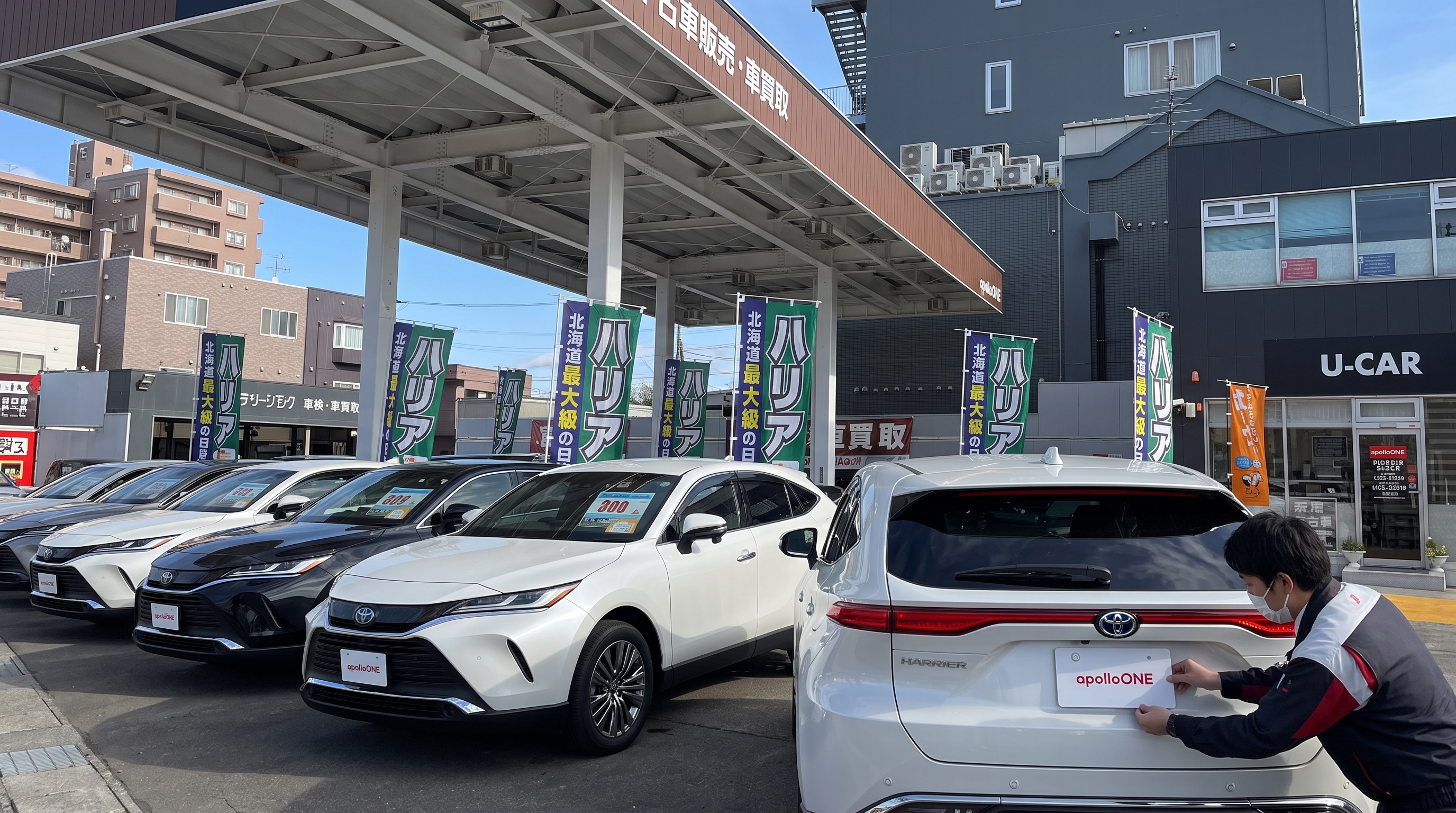 冬の店舗スペースにて、白いSUVのリアハッチを開け、スタッフが黄色のメジャーでトランクルームの幅を計測し、荷室のサイズ感や使い勝手を確認している手元の様子。