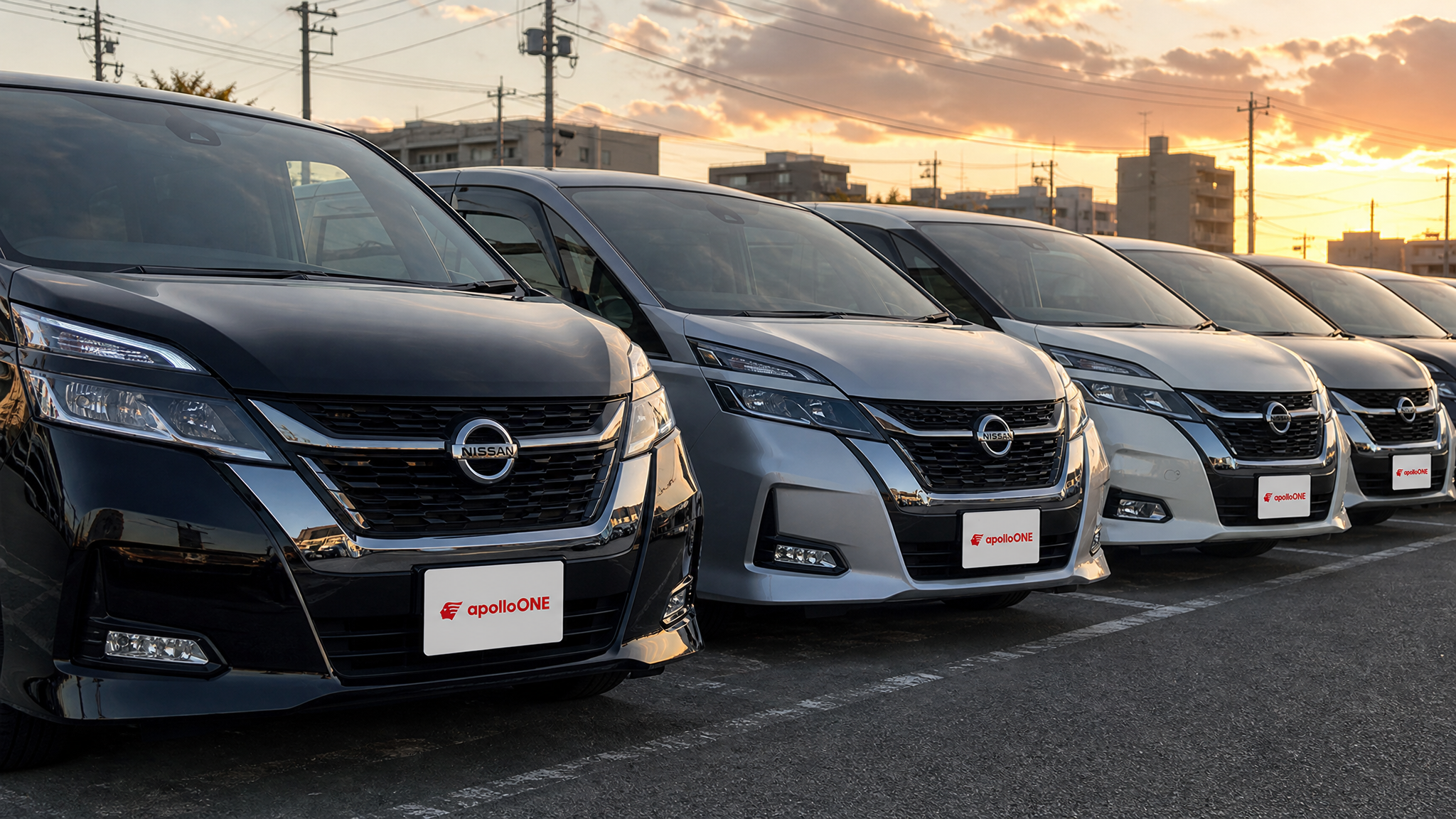 秋の夕暮れ時に、黒やシルバー、白など様々なボディカラーのミニバンが綺麗に整列して展示されている中古車展示場の様子。活気ある店舗の雰囲気が伝わるシーンです。
