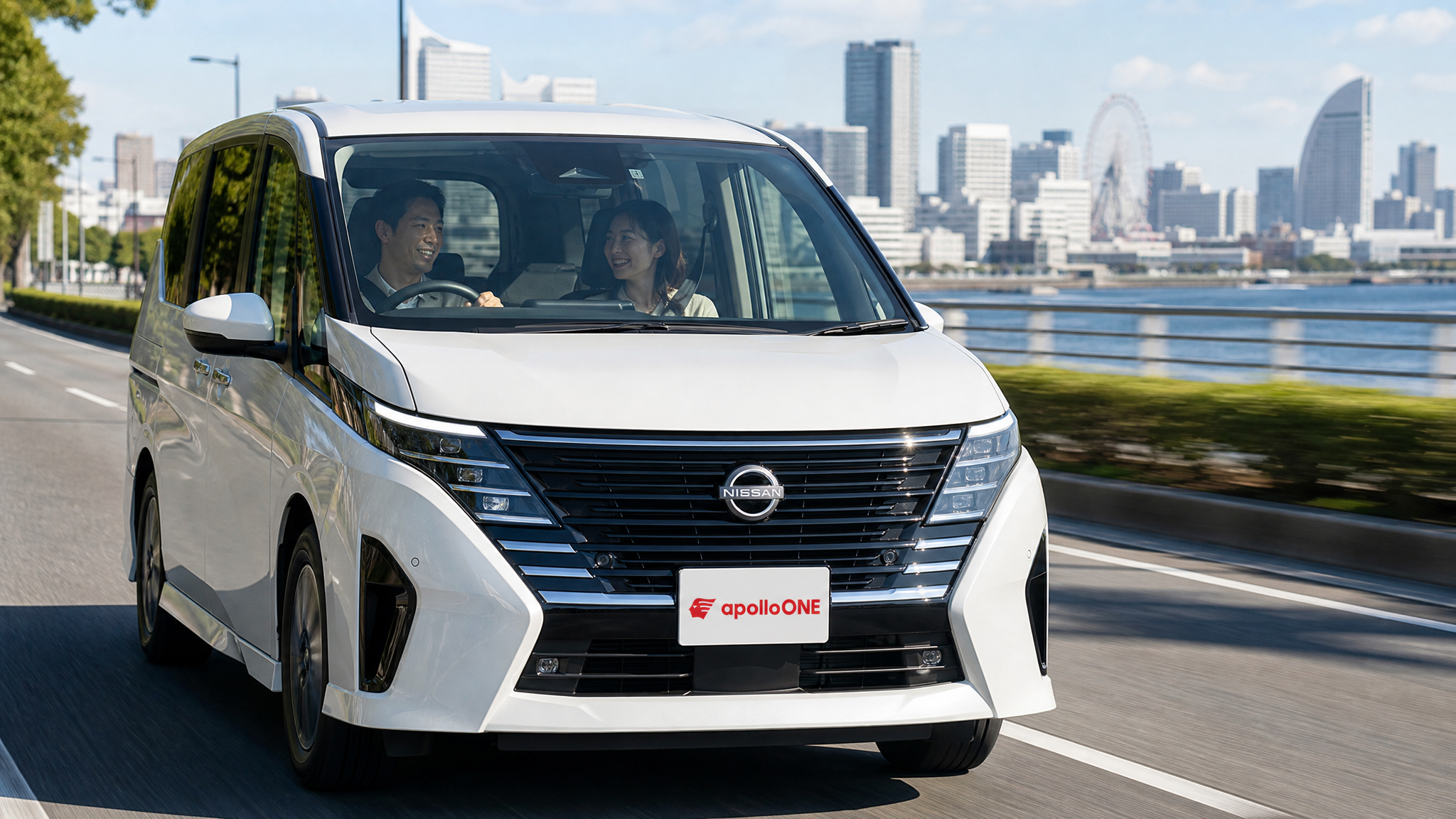 春の穏やかな昼下がり、海沿いの街並みを背景に、広いミニバンの車内で30代の夫婦がリラックスした笑顔を浮かべながらドライブを楽しんでいる走行中の様子。