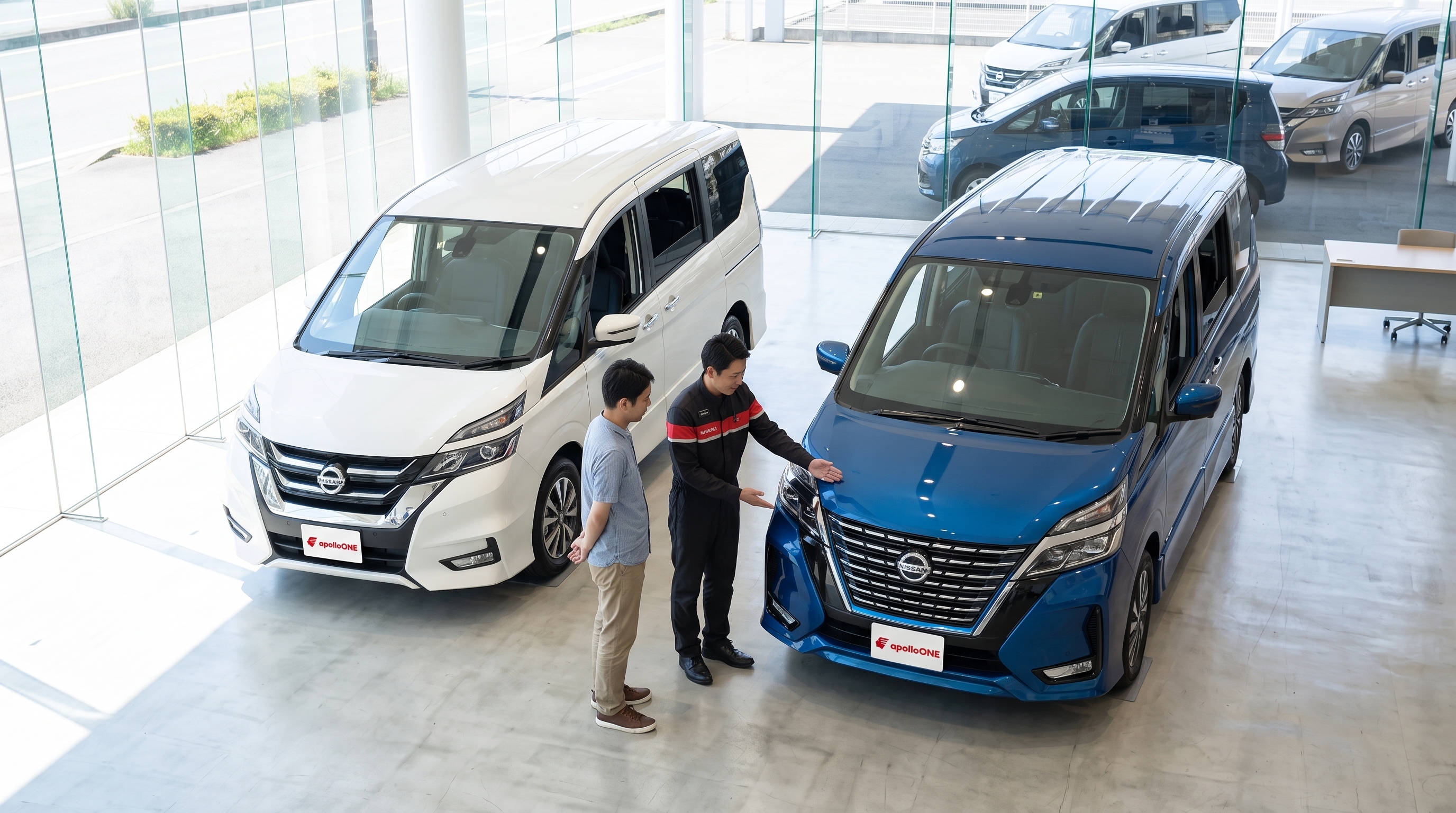 明るいショールームで、2台のミニバンのフロントデザインを見比べる顧客と販売員の俯瞰写真。販売員がフロントグリルの形状の違いを身振りで説明しているシーン。