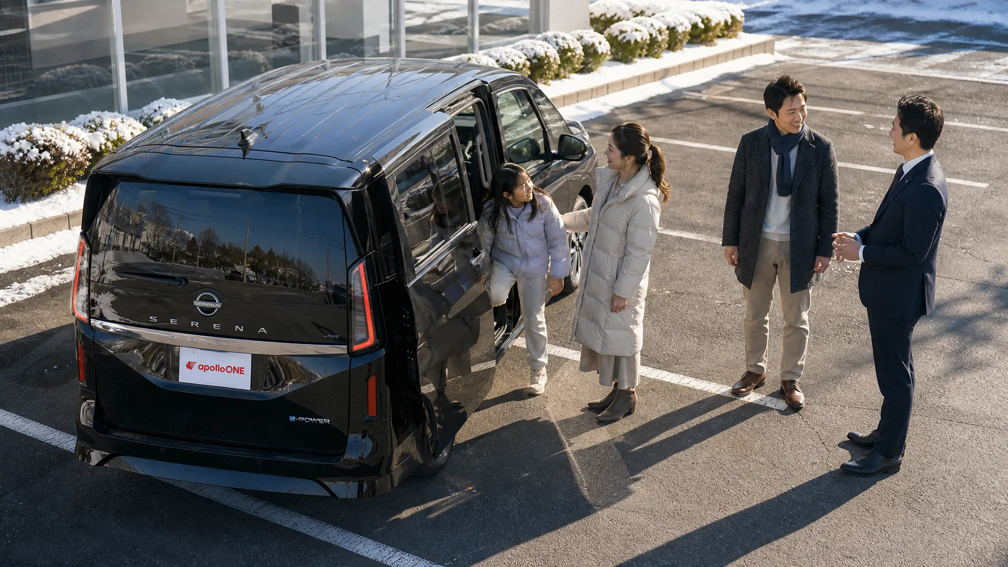 冬の澄んだ空気の中、駐車場で黒いミニバンの試乗を終えて車から降り、車の後方でスタッフと満足そうに感想を話し合って談笑する家族のハイアングルショット。