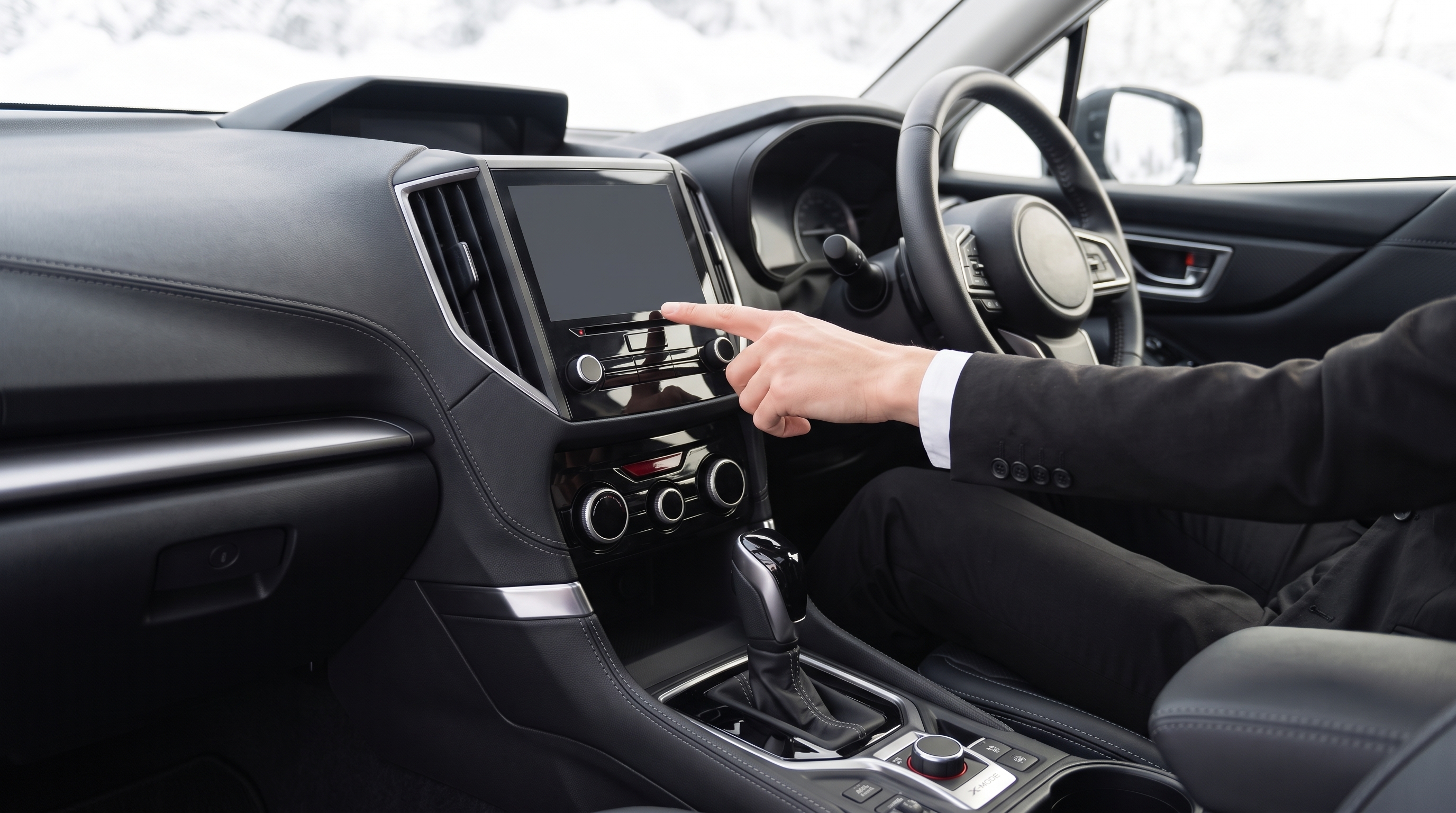 窓外の雪明りが照らす車内の様子。ダッシュボードの大型ディスプレイやスイッチ類に焦点を当て、運転席の販売スタッフが画面を指差して機能を説明しているクローズアップ。