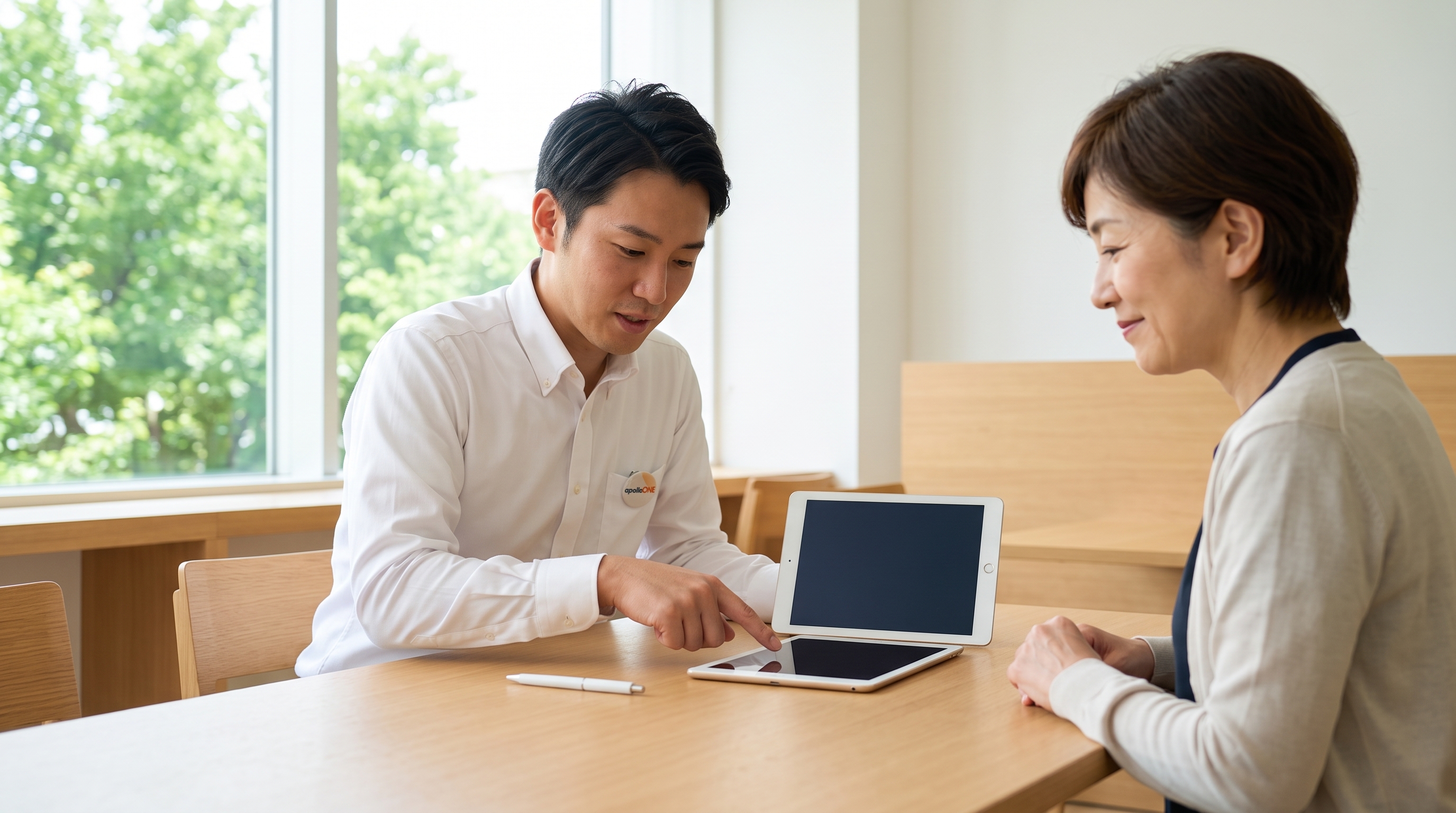 明るい窓辺の商談スペースで、スタッフがタブレット画面を指差しながらフォレスターの買取査定額を丁寧に説明し、顧客が納得した表情でうなずいているシーン。