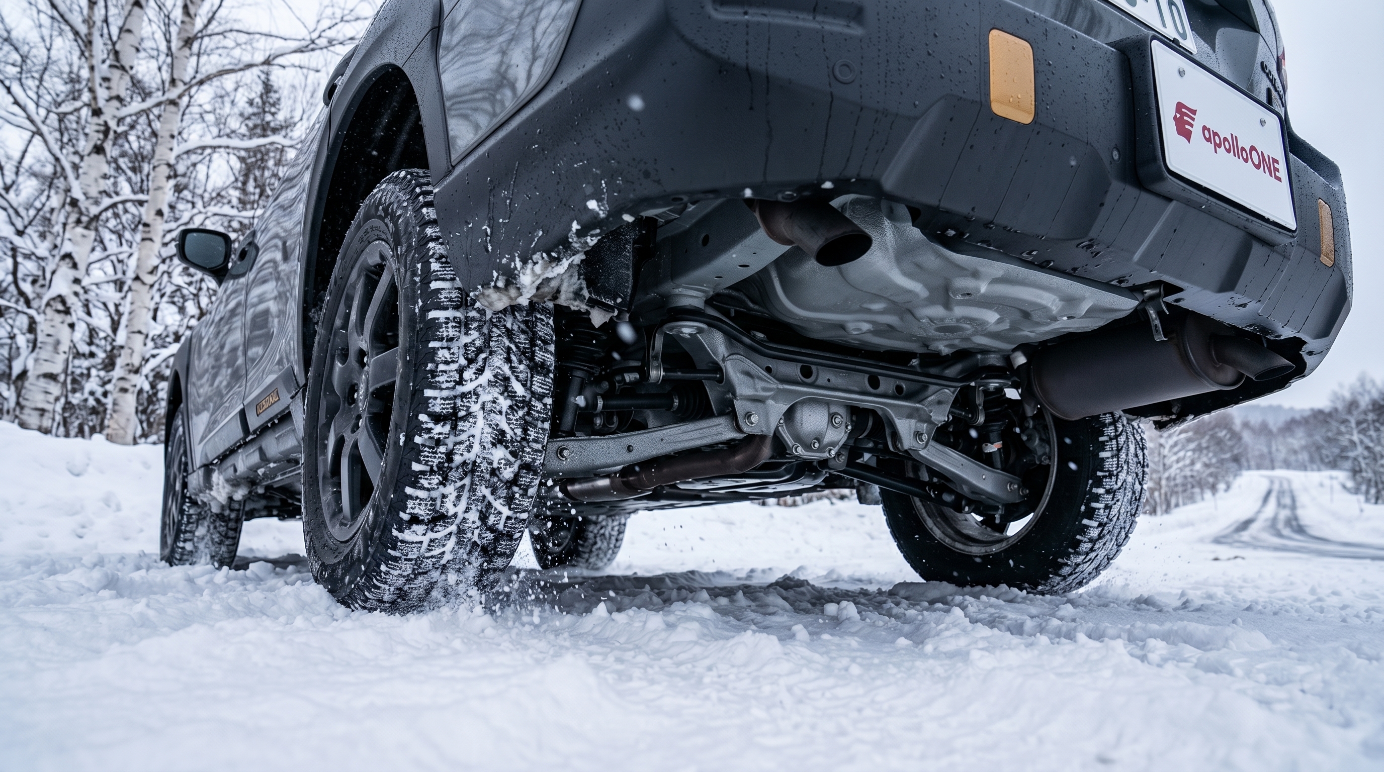 雪が積もった北海道の冬道を力強く走行するスバル車の足回りのクローズアップ。シンメトリカルAWDの安定感と防錆コーティングされた下回りを感じさせるアングル。