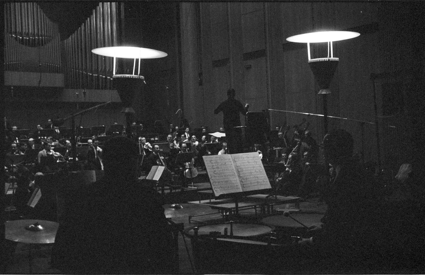 Probensituation: Blick auf das in Aktion befindliche Orchester, auf den Dirigenten Michael Gielen schauend, fotografiert von einer Position direkt hinter zwei Schlagzeugern