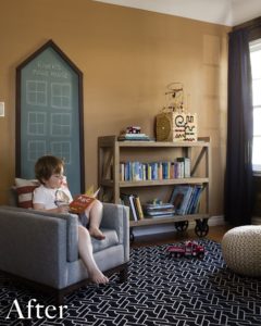 Child in a grey fabric chair with a blue rug and orange walls